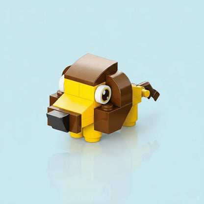 A small, cute lion made from yellow and brown building blocks with big eyes, placed against a clean light-blue background.